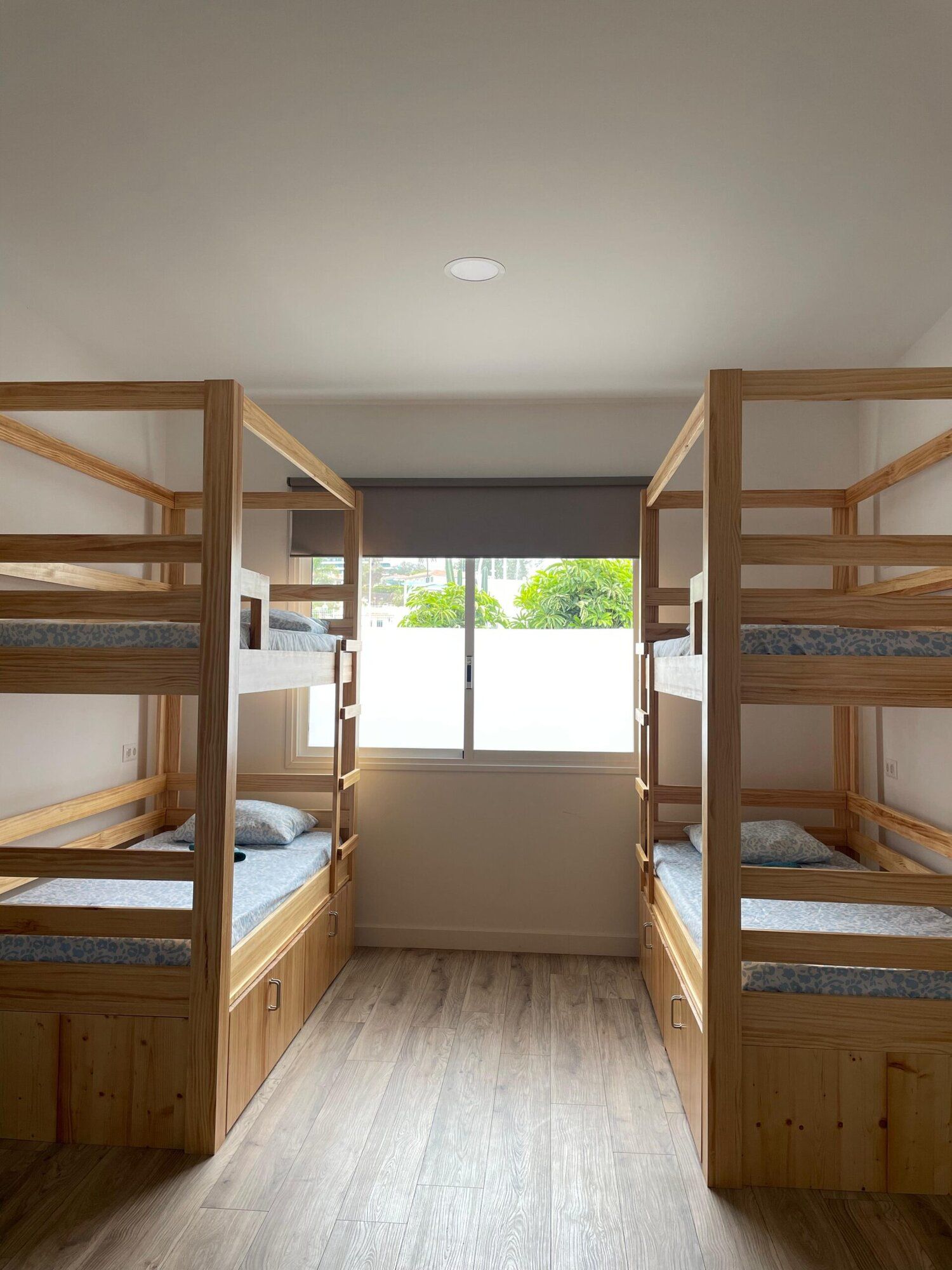Two pairs of wooden bunk beds facing each other, with storage drawers under the lower beds