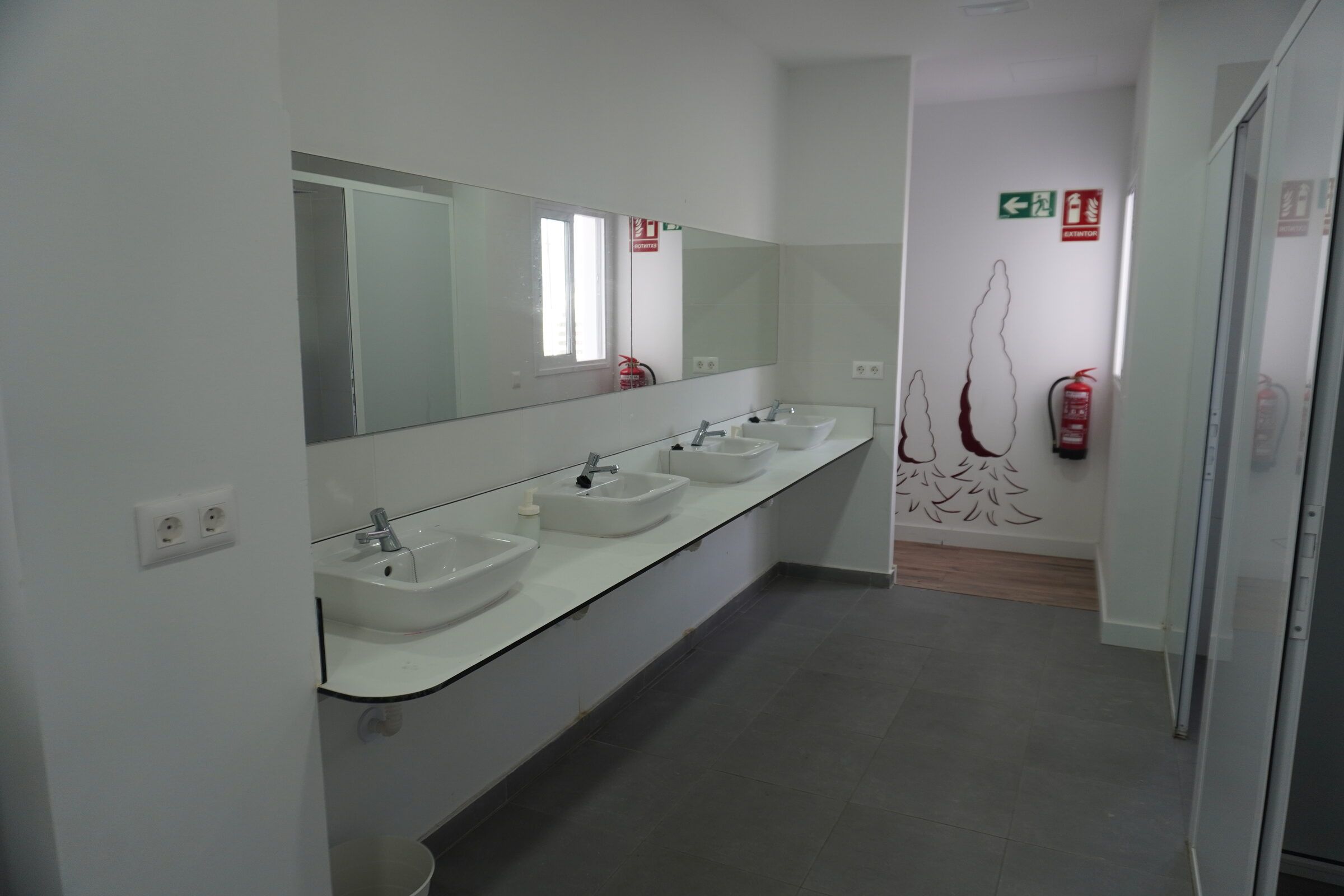 Shared bathroom on the second floor with a row of sinks, a long mirror and shower cubicles