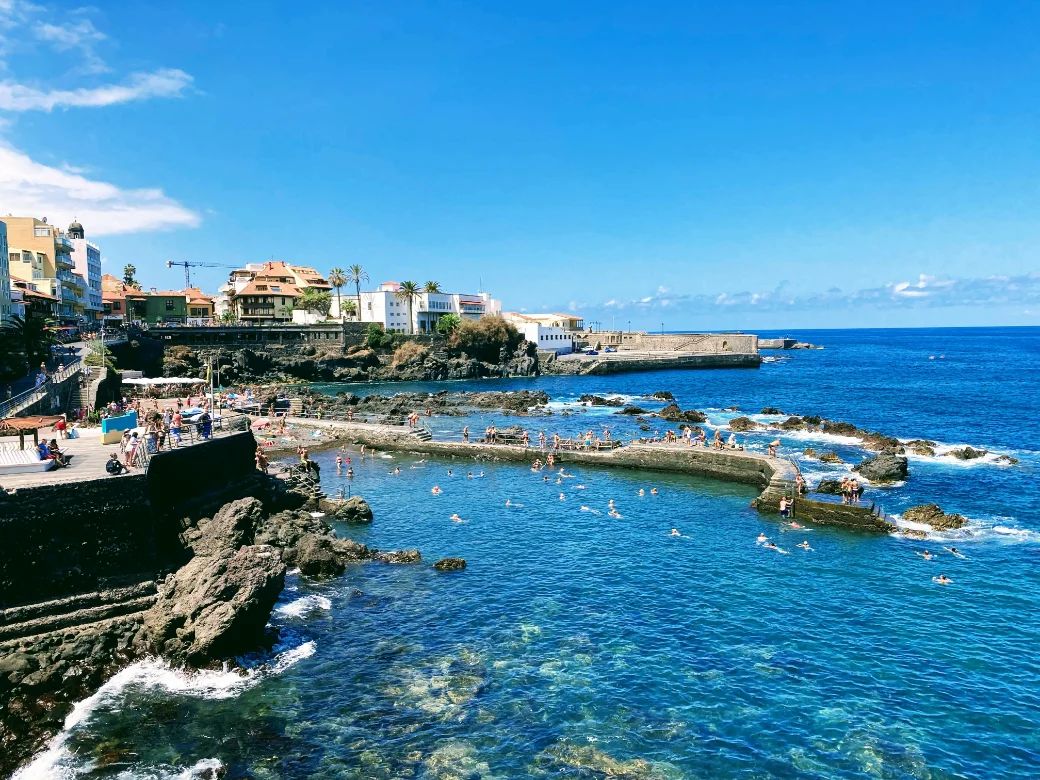 The seafront bathing pools and rooftops of Puerto de la Cruz on a clear day, with the Atlantic beyond