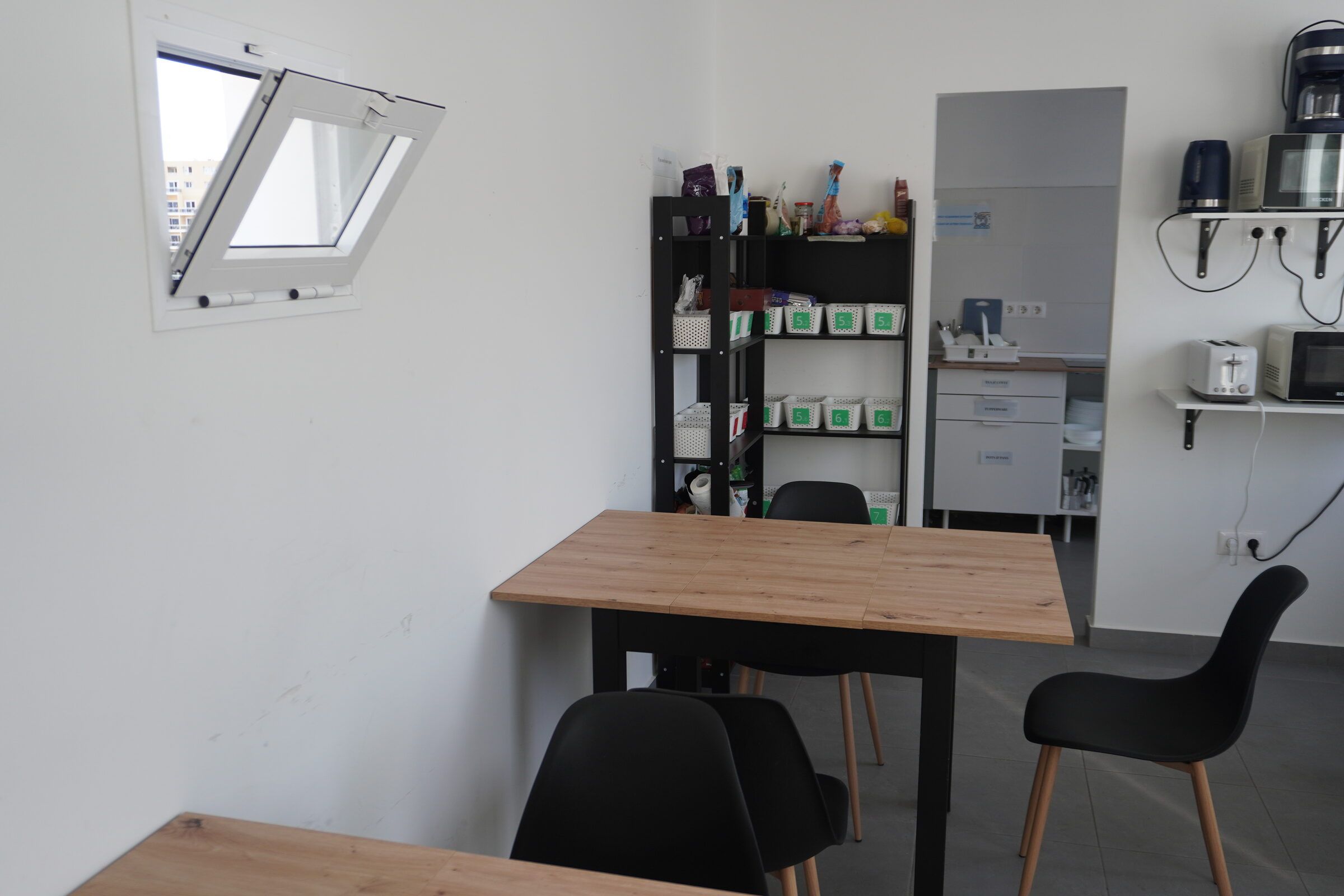 Shared kitchen with a wooden dining table, chairs and open shelves