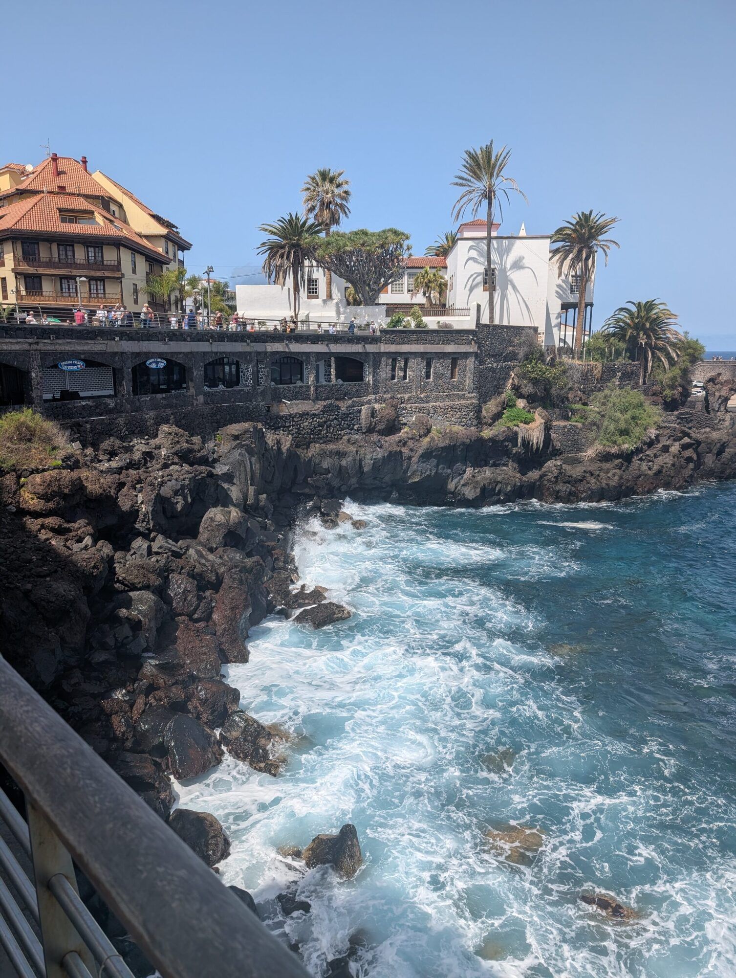 Waves breaking on black volcanic rocks below the old town of Puerto de la Cruz