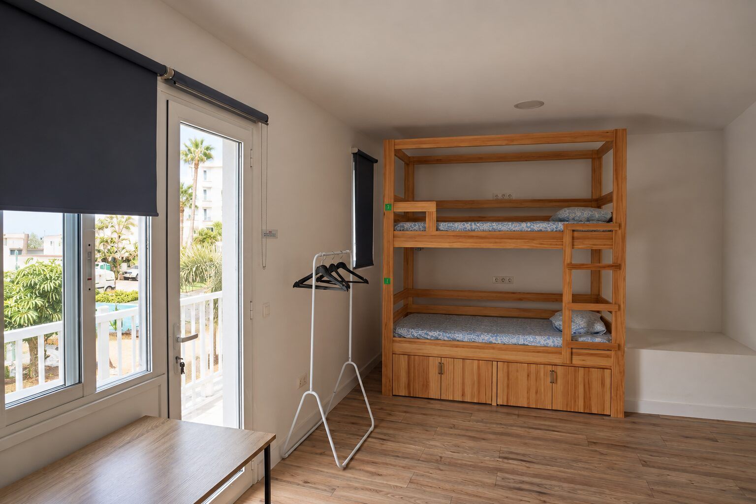 Room 7: bunk bed and clothes rail next to a large window and balcony door