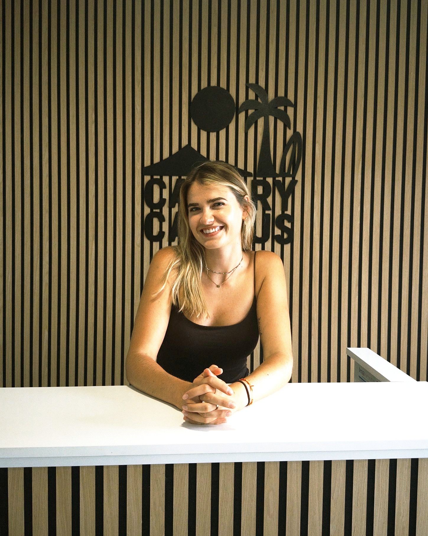 Benita, house manager at Canary Campus Hostel, smiling at the reception desk